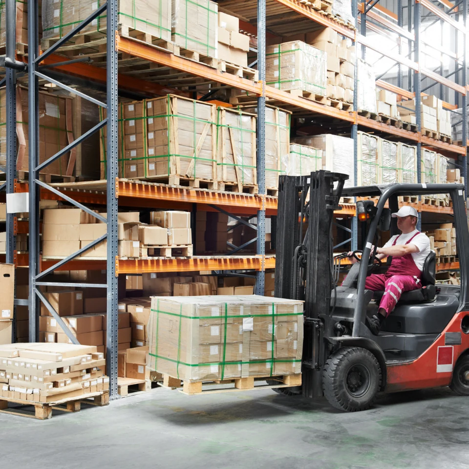 Forklift operator working beside warehouse storage racks